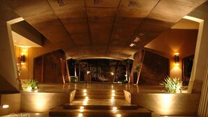 Eine Hotelhalle mit einer imposanten Treppe, warmer Beleuchtung und einem modernen Design.