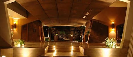 Un vestíbulo de hotel con una escalera monumental, iluminación cálida y diseño moderno.