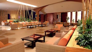 Un vestíbulo amplio con varias zonas de estar, incluyendo sofás y sillones, distribuidos alrededor de mesitas de café.