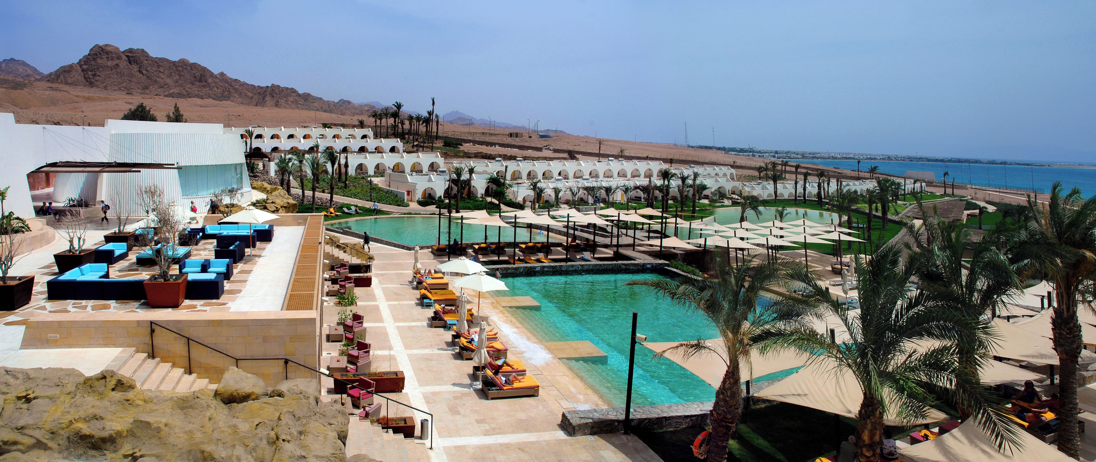 Un resort con varias piscinas, zonas de descanso y vistas al mar.