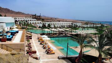 Un resort con varias piscinas, zonas de descanso y vistas al mar.