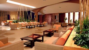 Eine großzügige Lobby mit mehreren Sitzbereichen, darunter Sofas und Sessel, die um Couchtische angeordnet sind.