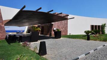 A modern building with a stone facade, a covered outdoor area with seating, and a cobblestone path.