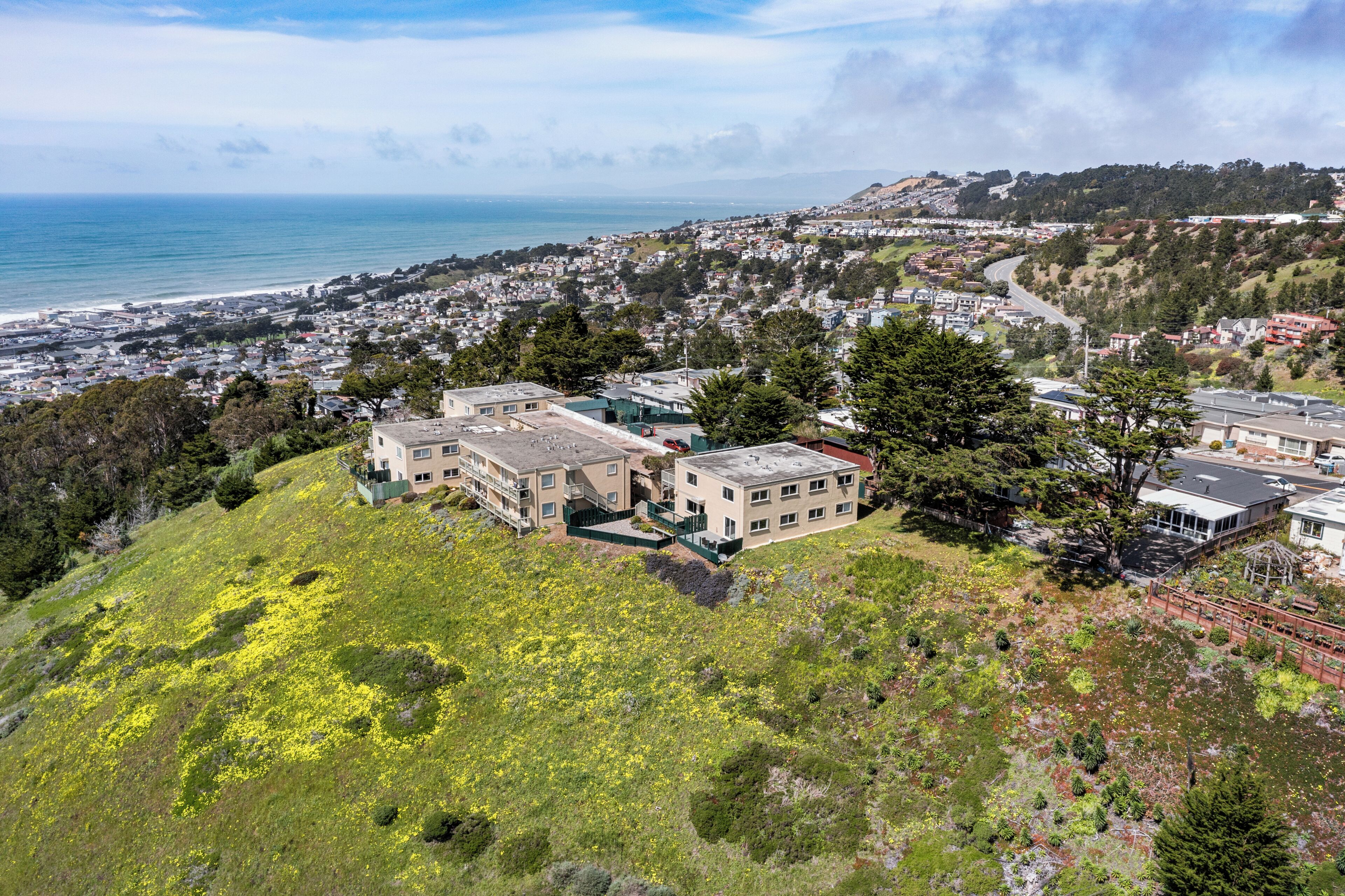 Área residencial com casas numa encosta, com vista para uma vila costeira.