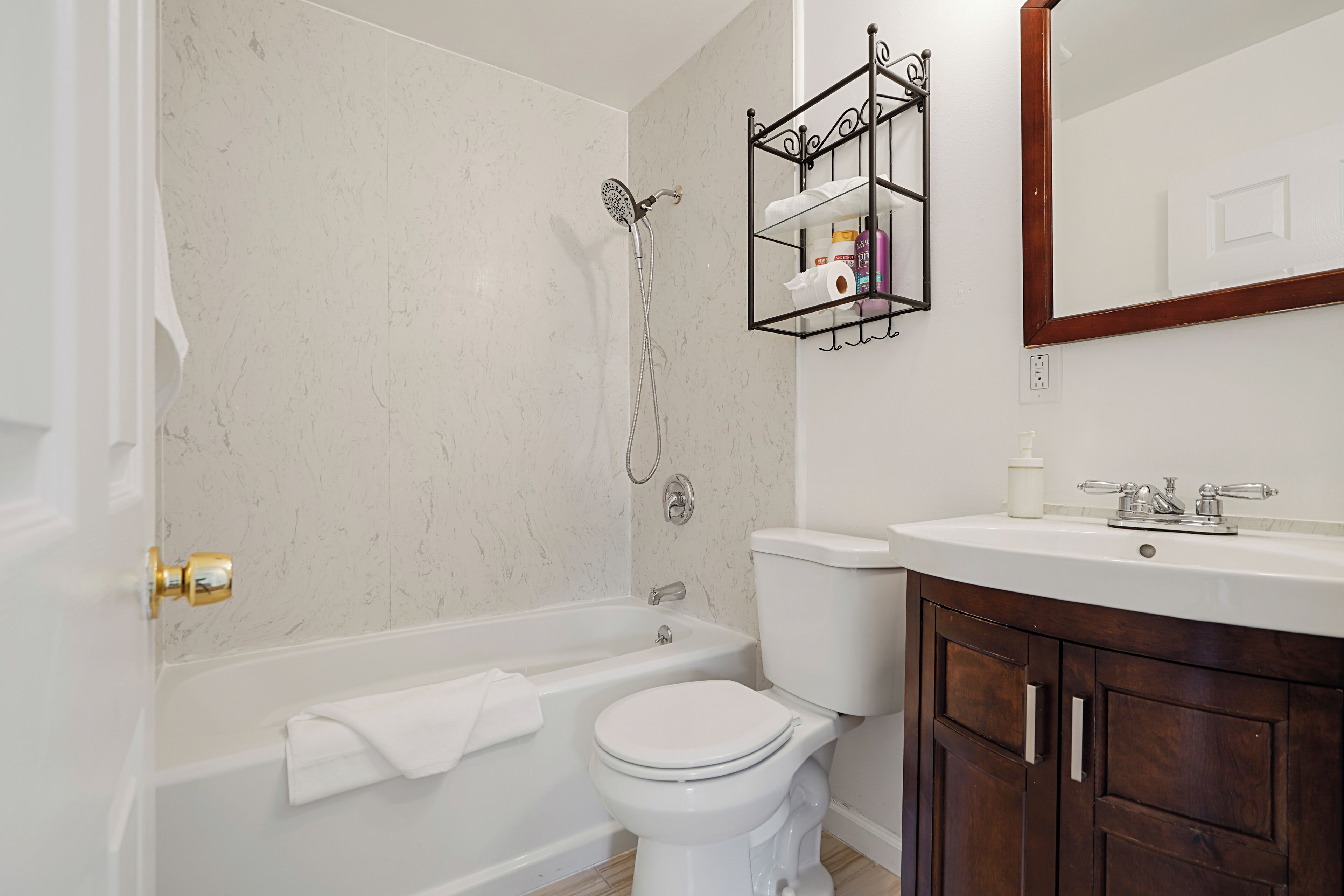 A bathroom with a bathtub, toilet, and sink. There is a towel rack above the sink and a mirror above the toilet.