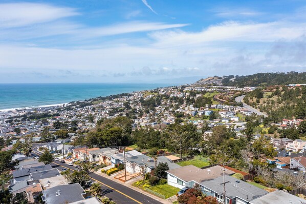A coastal residential area with houses, a road, and a view of the ocean. - Tranquil 2BR with Coastal Mountain Views (Pacifica)