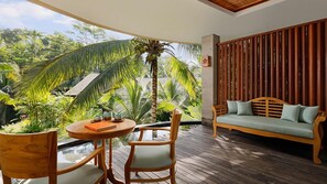 A wooden deck with a round table and chairs, a sofa, and a view of tropical foliage. - Abisena Wellness & Resort Ubud Adult Only (Tegallalang)