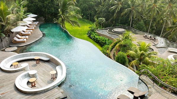 Un área de piscina con sillones de descanso y una zona de estar circular.
