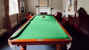 A room with a pool table, a fireplace, and a billiards table.