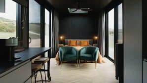 A bedroom with a bed, a desk, and a chair, large windows, and a view of the outdoors. - Cabn Kangaroo Island (Ironstone)