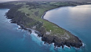 An aerial view of a coastal landscape with a narrow strip of land leading to a body of water, surrounded by green fields and rocky terrain. - Cabn Kangaroo Island (Ironstone)