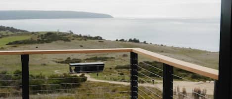 A balcony with a view of a coastal landscape, including a body of water and distant land.