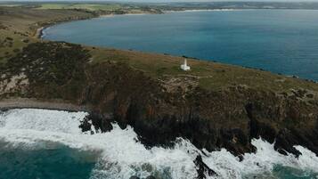 A coastal landscape with a lighthouse, rocky cliffs, and a body of water.