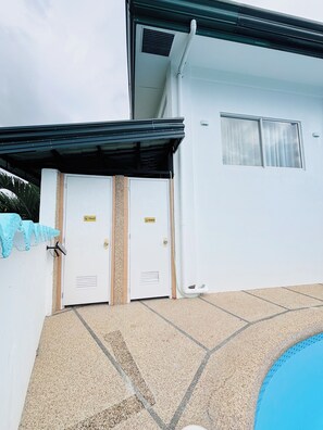 bathroom area with toilet and shower, featuring a beige tiled floor and a window.