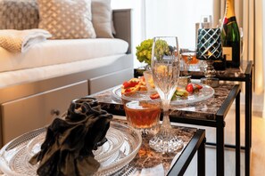 Een eettafel met een glas amberkleurig vocht, een decoratief glas en een fles champagne.
