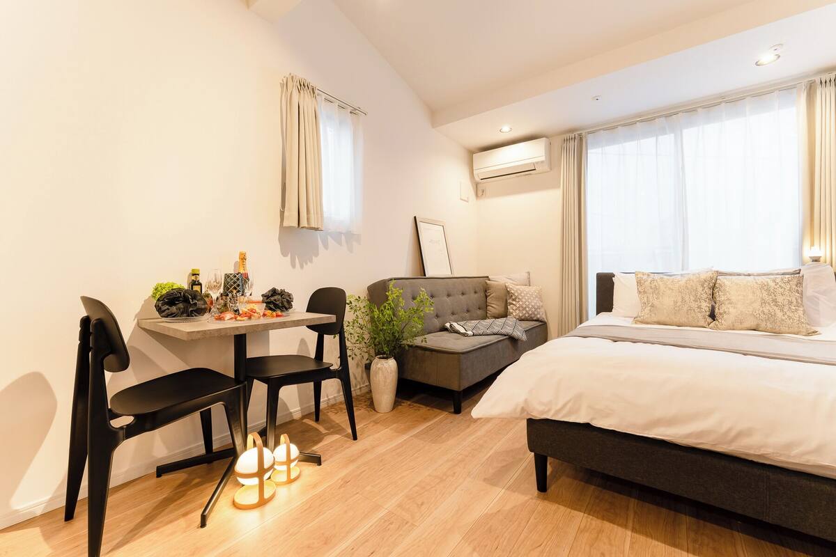 Una camera da letto moderna con un letto, un divano, un tavolo da pranzo con sedie e un condizionatore.