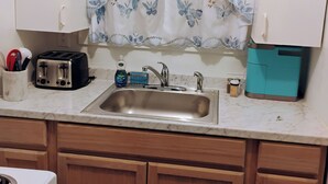 A kitchen with a sink, a toaster, a kettle, and a cabinet. - Charming 1-bedroom cottage in Port Orange Close to Daytona Beach  (Port Orange)