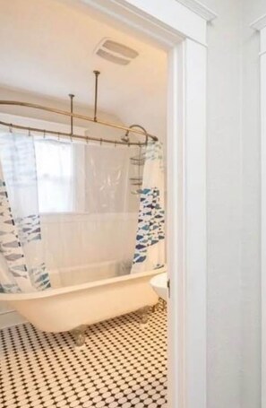 A bathroom with a freestanding bathtub, a shower curtain, and a patterned floor. - Kadia’s Place-The One With The Private Backyard (Cedar Rapids)