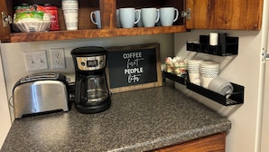 Una cocina con cafetera, tostadora y un letrero que dice "COFFEE first PEOPLE later".