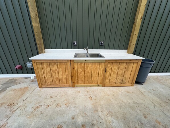 A wooden kitchen island with a sink and cabinets, against a green wall.