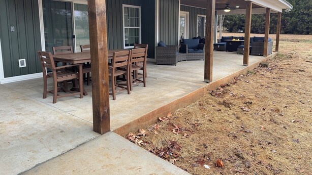A covered patio area with a dining table and chairs, a seating area with sofas and cushions, and a wooden deck.