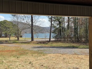 A view from inside a building looking out to a lake surrounded by trees and mountains.