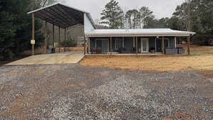 A single-story building with a covered patio area and a gravel driveway.