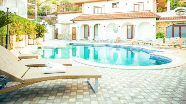 Une piscine avec des chaises longues et un sol carrelé.
