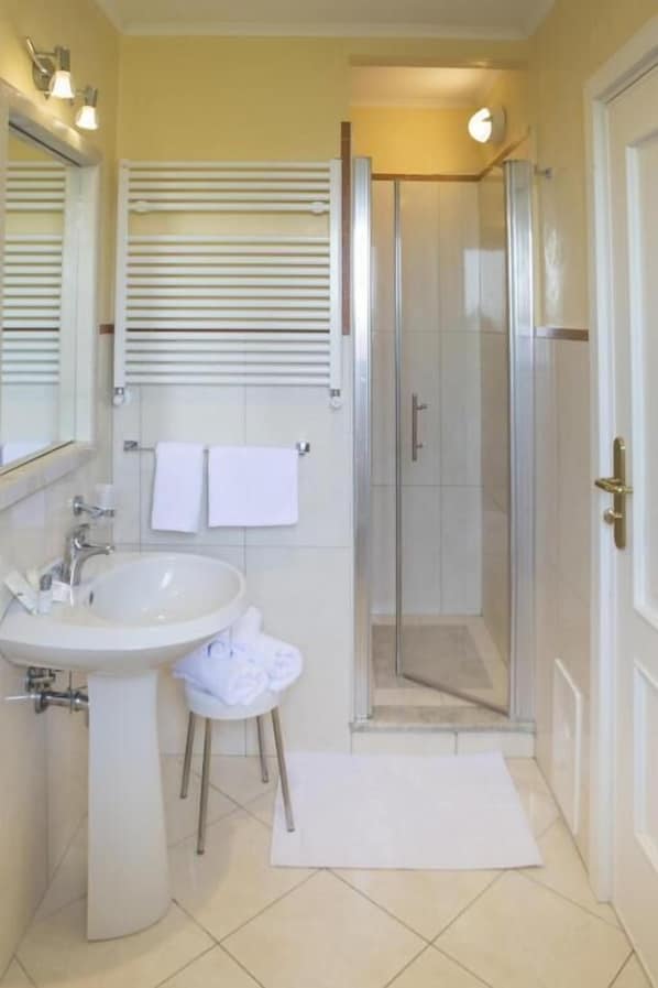 A bathroom with a sink, mirror, towel rack, and a glass-enclosed shower. - Villa Donna Carmela (Pimonte)