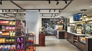 Un patio de comidas moderno con diversas opciones de bocadillos, un área de descanso y una pantalla digital con el menú.