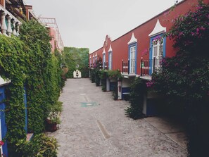 A narrow alleyway with buildings on either side, some with balconies and greenery. - Meson Yollotl (Puebla)