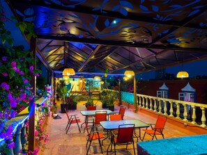 An outdoor patio area with tables and chairs, potted plants, and a decorative ceiling. - Meson Yollotl (Puebla)