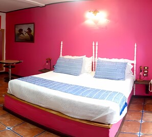 A bed with a white headboard, blue bedding, and a red wall. - Meson Yollotl (Puebla)