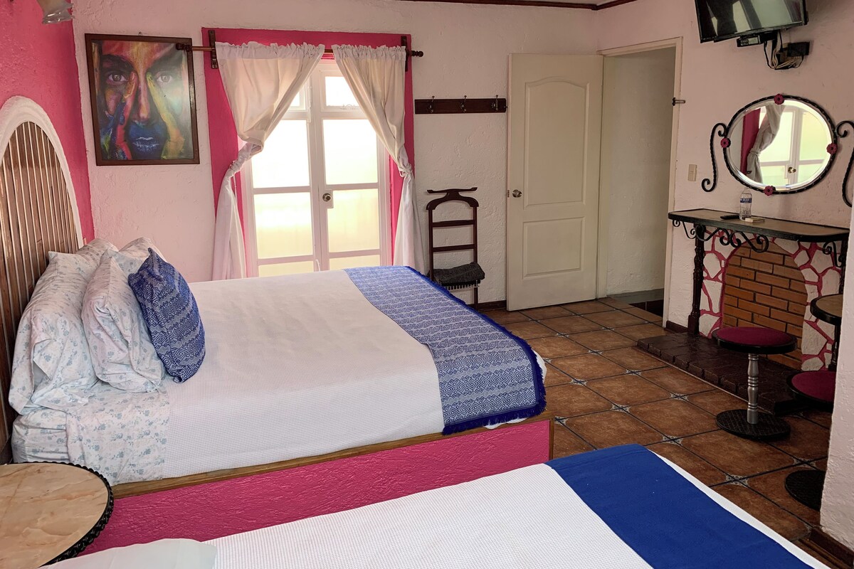 A bedroom with a bed, a chair, a TV, and a door.