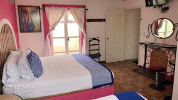 A bedroom with a bed, a chair, a TV, and a door.