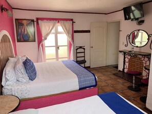 A bedroom with a bed, a chair, a TV, and a door. - Meson Yollotl (Puebla)