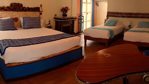 A hotel room with two beds, a wooden headboard, a small table, and a chair. - Meson Yollotl (Puebla)