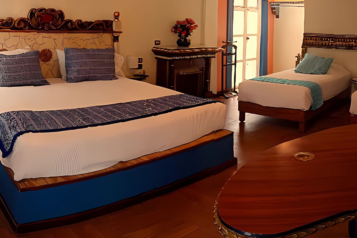 A hotel room with two beds, a wooden headboard, a small table, and a decorative mirror.