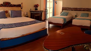 A hotel room with two beds, a wooden headboard, a small table, and a decorative mirror.