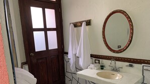 A bathroom with a white sink, a mirror, and a door with frosted glass panels. - Meson Yollotl (Puebla)