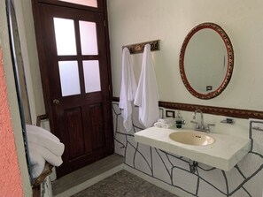 A bathroom with a white sink, a mirror, and a door with frosted glass panels. - Meson Yollotl (Puebla)