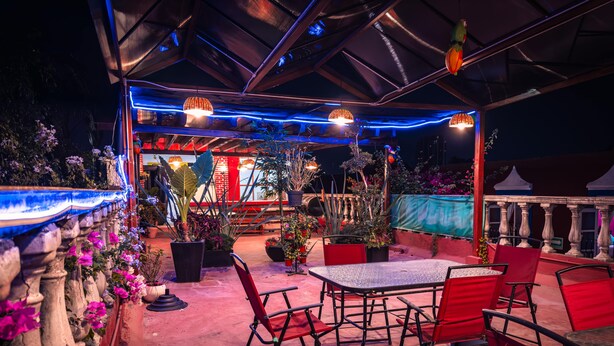 An outdoor patio with a table and chairs, surrounded by potted plants and flowers. - Meson Yollotl (Puebla)