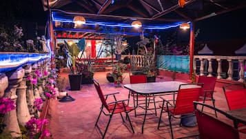 An outdoor patio with a table and chairs, surrounded by potted plants and flowers.