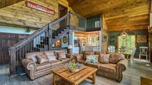 A spacious log cabin interior with a dining area, a kitchen, and a staircase leading to an upper level. - Family Friendly Getaway I Hot Tub In Gatlinburg (Gatlinburg)