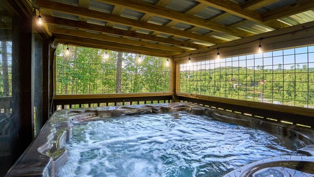 A hot tub with a wooden ceiling and large windows overlooking a forested area. - Family Friendly Getaway I Hot Tub In Gatlinburg (Gatlinburg)