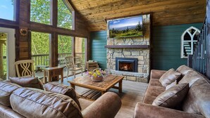 A cozy cabin interior with a stone fireplace, leather sofas, and a wooden ceiling. - Family Friendly Getaway I Hot Tub In Gatlinburg (Gatlinburg)