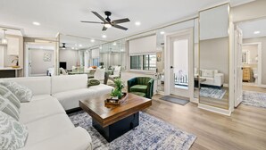 A modern living room with a sectional sofa, a wooden coffee table, and a green armchair.