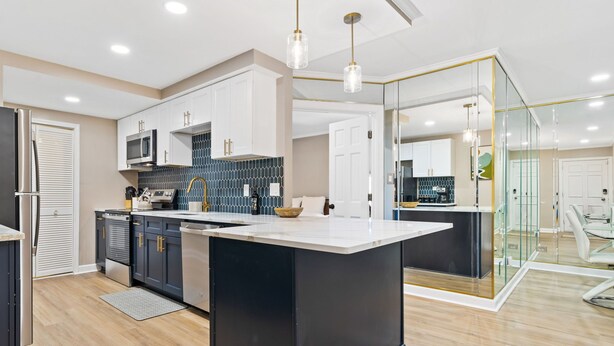 A modern kitchen with a central island, white cabinets, and a glass partition.