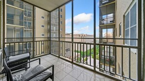 A balcony with a view of neighboring buildings and a clear sky.