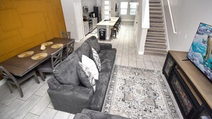 A modern living room with a sofa, coffee table, and TV. There is a staircase leading to another level. - Family place to feel at home 🏡 ! Close to everything and where you'll find it all (Kissimmee)